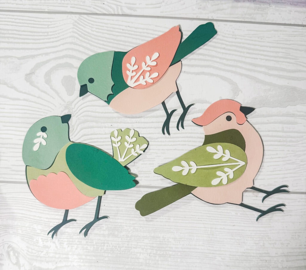 Colorful paper bird decorations with leaf details, perfect for home decor or craft projects, showcasing handmade artistry and nature-inspired design.