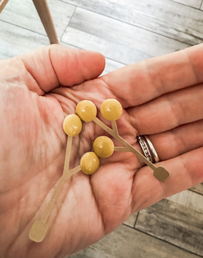 A close-up of a small branch with yellow berries held in a person's hand, showcasing natural details and textures, perfect for nature or botanical themes.