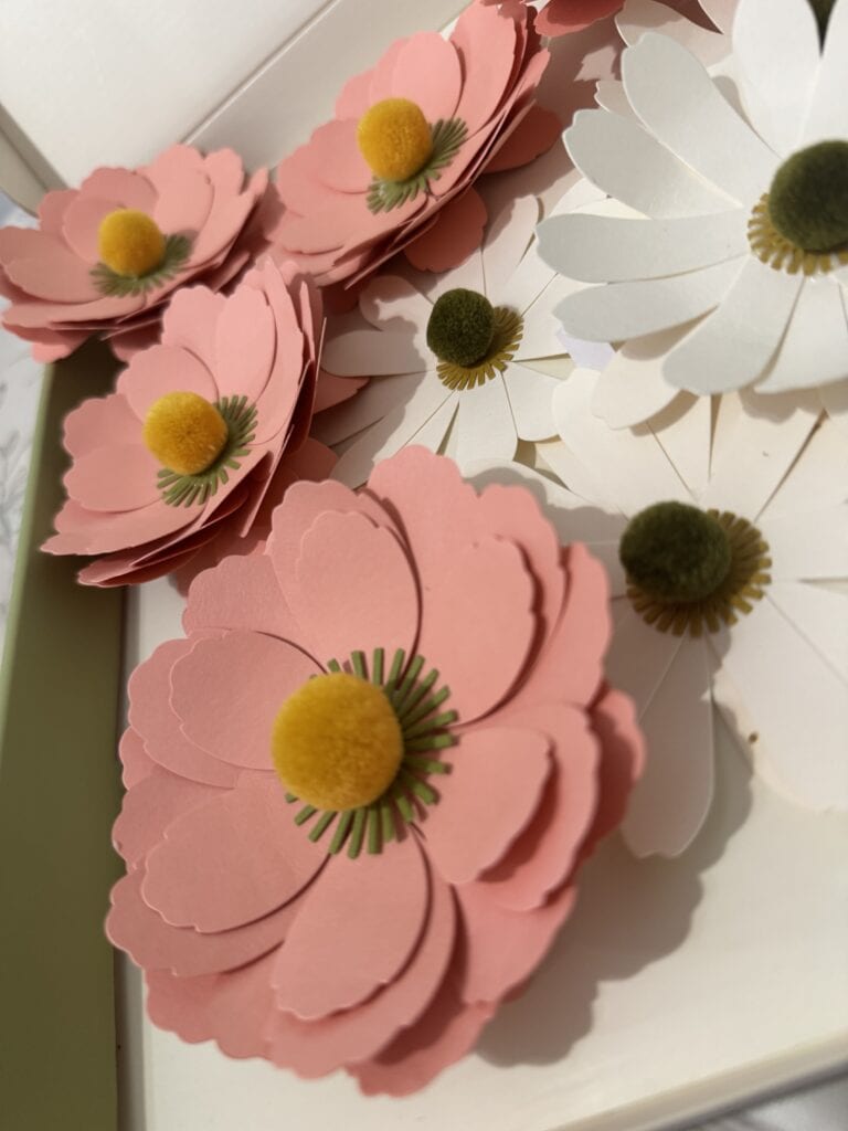 Bright pink and white paper flowers with yellow and green centers, perfect for spring decor or craft projects.