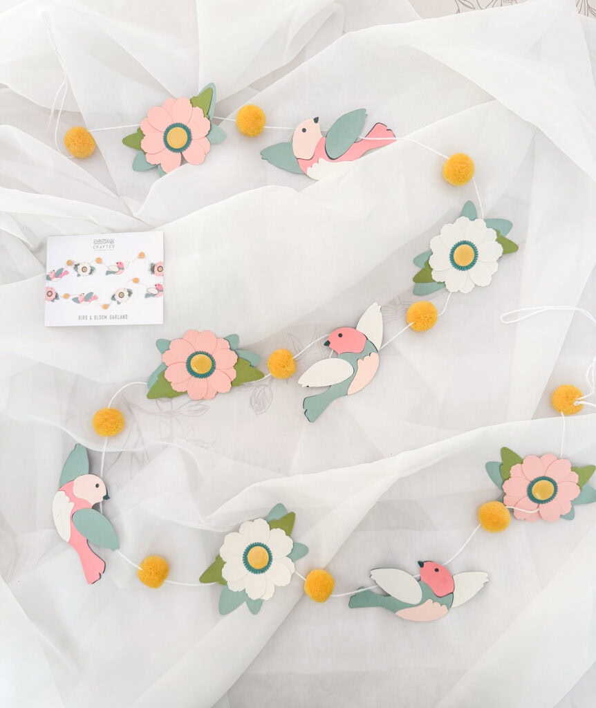 Colorful paper flower and bird garland, perfect for baby shower, nursery decor, or spring celebration, featuring pastel pink, white, and green tones with yellow accents.