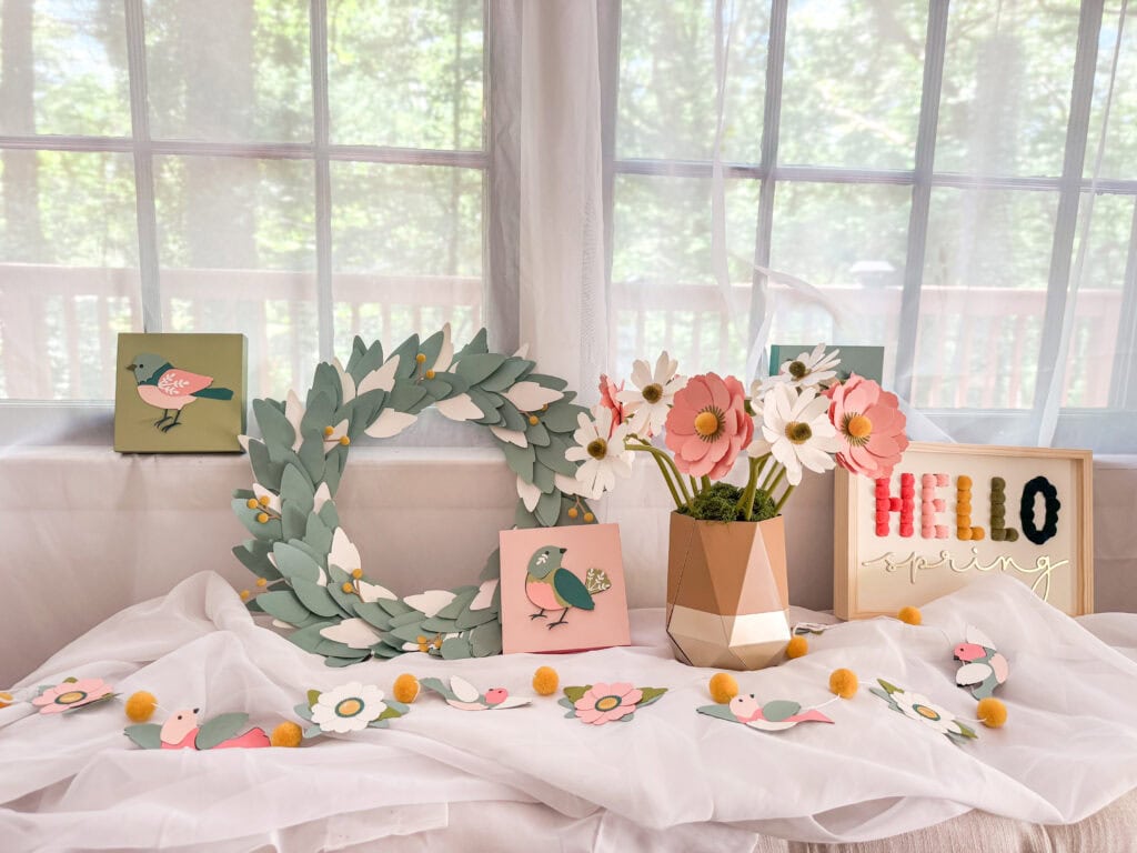 Bright floral and bird-themed decor arrangement with paper flowers, a leafy wreath, and cheerful accents for a cozy, welcoming space.