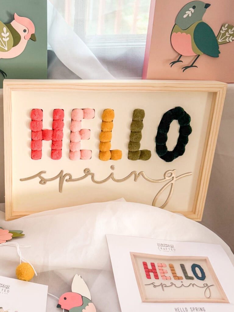 A decorative sign spelling "HELLO spring" with colorful letter cookies for "HELLO" and elegant script for "spring," celebrating the arrival of spring with cheerful decor.