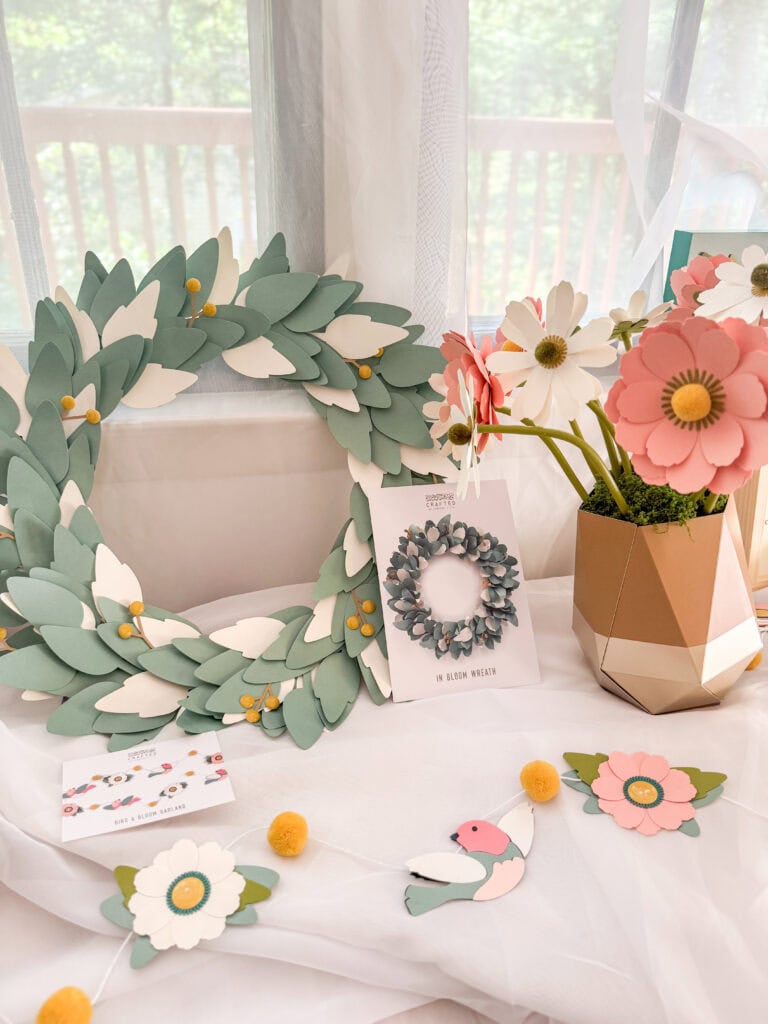 Colorful paper flower arrangement with wreath, floral decor, and craft accessories for spring and wedding celebrations.