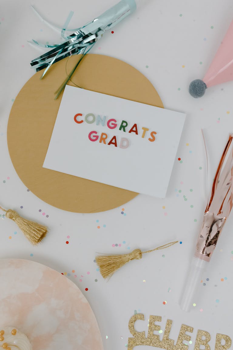Bright and cheerful graduation celebration scene with confetti, party hats, and a congratulatory card reading "CONGRATS GRAD" for a joyful graduation event.
