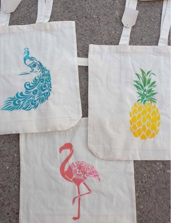 Colorful tote bags featuring a blue peacock, pink flamingo, and yellow pineapple, perfect for summer accessories and eco-friendly shopping.