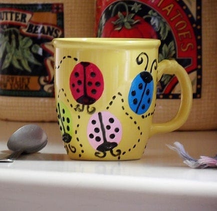 Bright yellow ceramic mug featuring whimsical ladybug designs in red, blue, and pink, ideal for adding charm to your morning routine or as a gift.