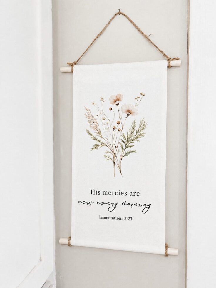 Beautiful fabric wall hanging featuring a delicate botanical illustration and inspirational quote, perfect for home decor.