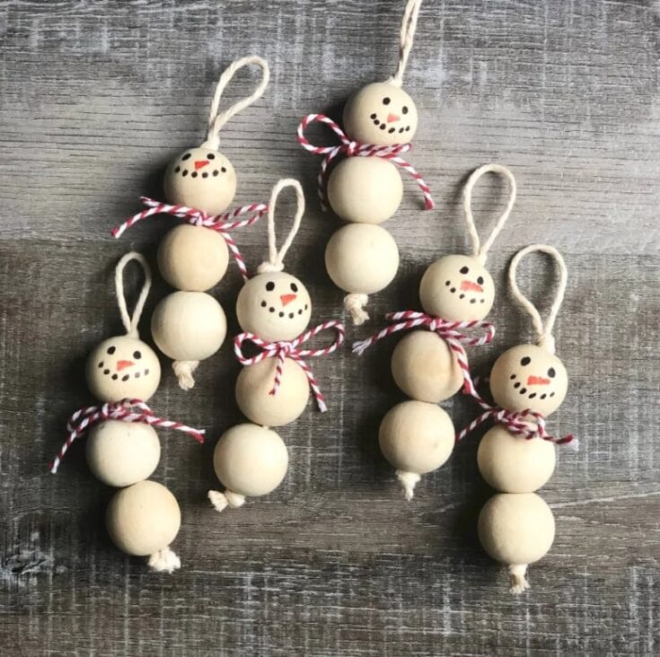 Set of six handcrafted wooden snowman ornaments with painted faces, red and white striped scarves, and hanging loops, perfect for holiday decor.