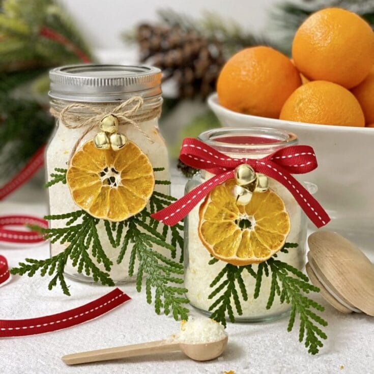 Decorative glass jars with dried citrus slices, festive ribbons, and greenery, perfect for holiday gift-giving and home decor from A Hundred Affections.