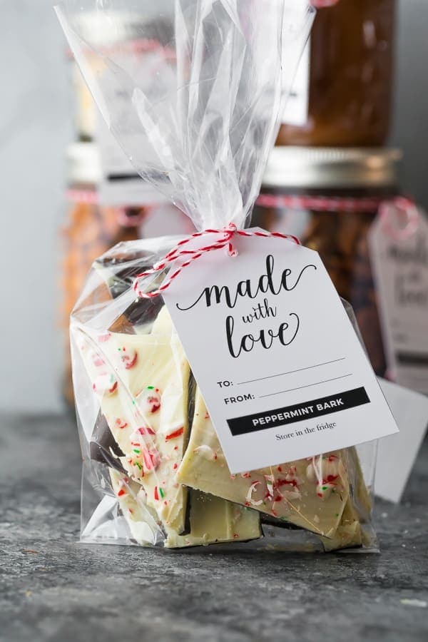 Clear plastic bag filled with homemade peppermint bark, tied with red and white string, featuring a 'made with love' tag for holiday gifting.