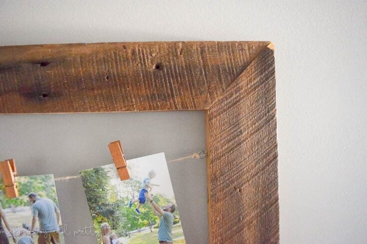 A family having a joyful outdoor picnic with photos hanging on a rustic wooden frame, capturing happy moments in a natural setting.