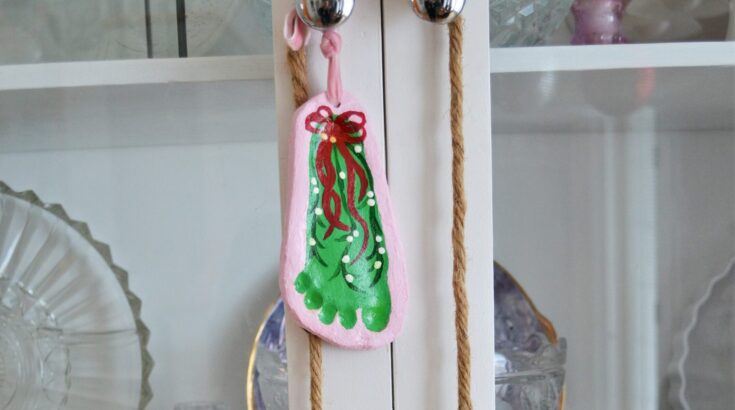 Colorful Christmas stocking with green, red, and pink details hanging on a white cabinet door, decorated for the holiday season.