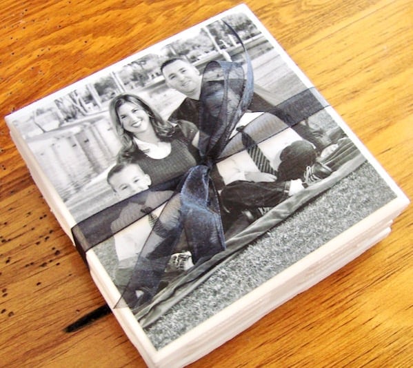 A custom photo album featuring a black-and-white family picture tied with a navy blue ribbon, placed on a wooden surface, ideal for preserving special memories.