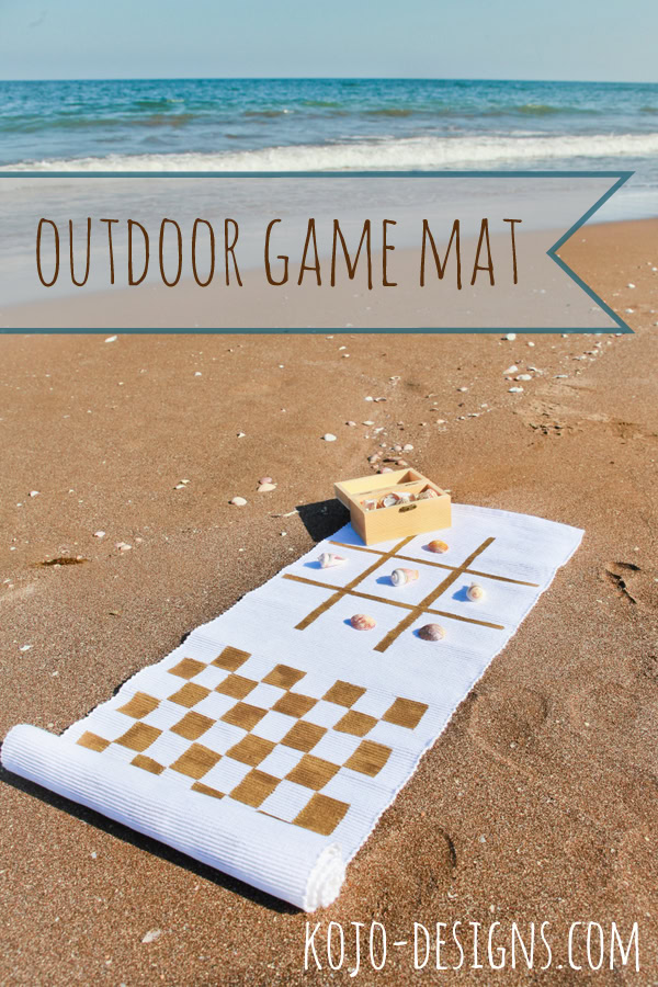 Beach scene with a white outdoor game mat featuring checkered and grid patterns, perfect for family outdoor activities by the sea.