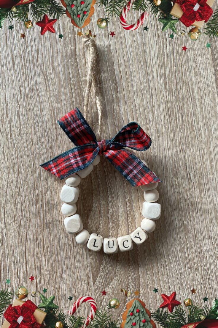 Handmade Christmas ornament with white beads spelling 'LUCY' and a plaid ribbon bow, perfect for holiday decor and gift-giving.