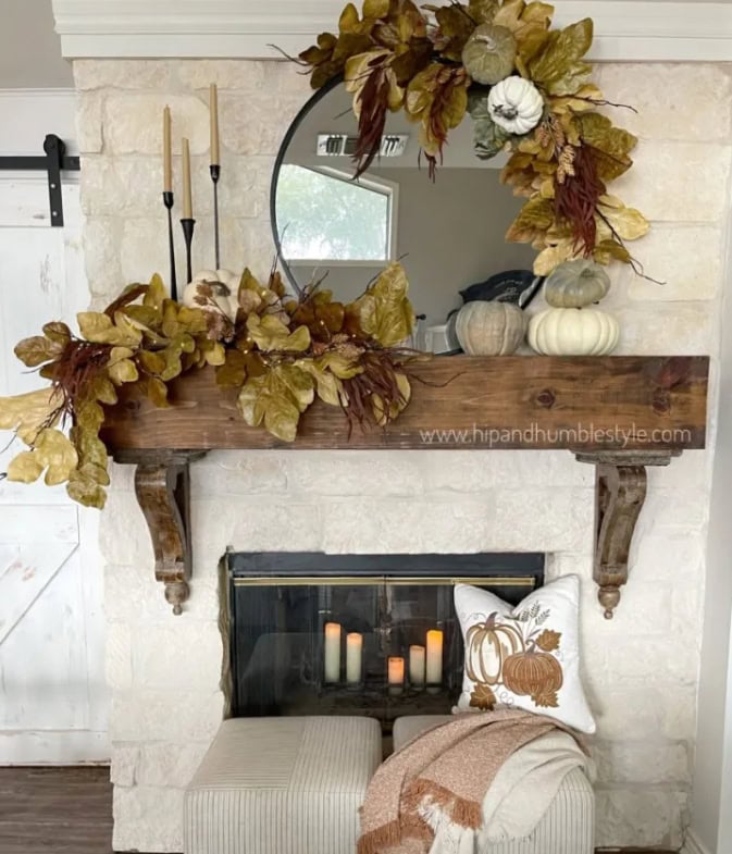 Fall-inspired fireplace mantel decorated with pumpkins, candles, and autumn leaves for cozy fall home decor.