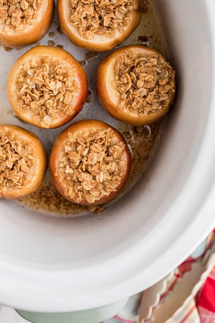 Baked apples filled with oatmeal and cinnamon in a white baking dish, perfect for fall desserts and cozy seasonal recipes.