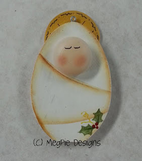 Cute baby angel ornament with closed eyes, rosy cheeks, and a small holly decoration, perfect for Christmas decor and holiday celebrations.