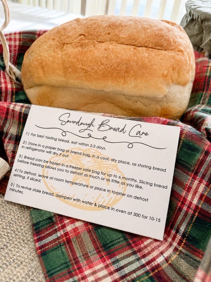 Freshly baked sandwich bread on a plaid cloth with a handwritten recipe card for bread care and baking tips.
