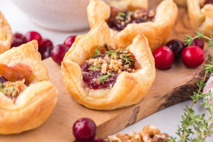 Delicious cranberry and walnut pastry bites with flaky golden crust, garnished with fresh cranberries and herbs, perfect for holiday gatherings and desserts.