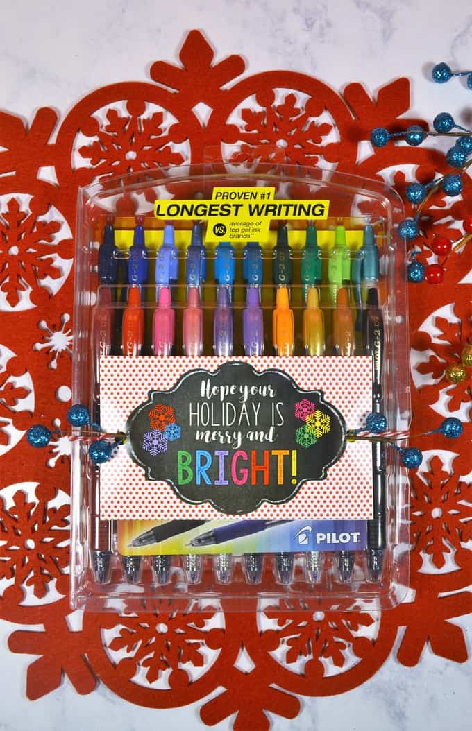 Set of colorful Pilot pens with a holiday-themed card reading 'Hope your holiday is merry and bright!' on a festive red and white background with snowflake patterns.
