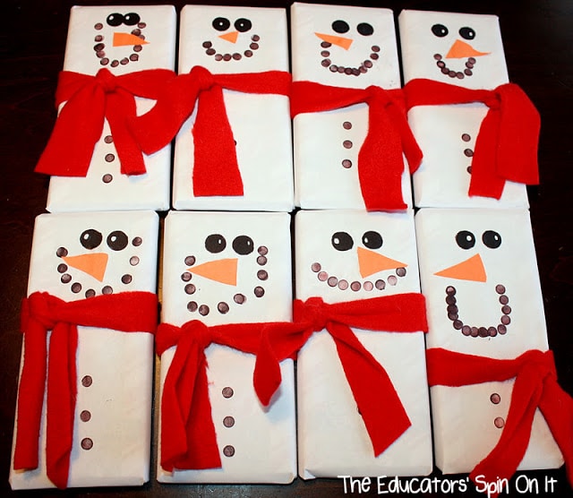 Festive snowman-themed gift wrapping with white paper, black buttons, orange noses, and red ribbons for holiday gift giving.