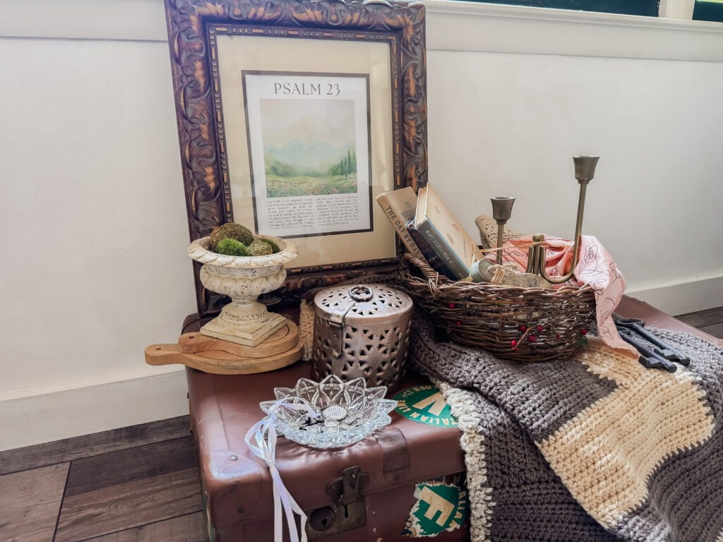 A decorative Bible verse display with framed Psalm 23, candles, a woven basket, and a cozy blanket on a wooden surface, creating a peaceful and spiritual ambiance.