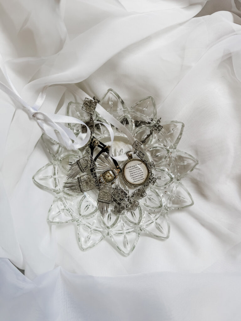 A collection of elegant jewelry including rings and necklaces arranged on a decorative glass plate, set on soft white fabric for a luxurious presentation.