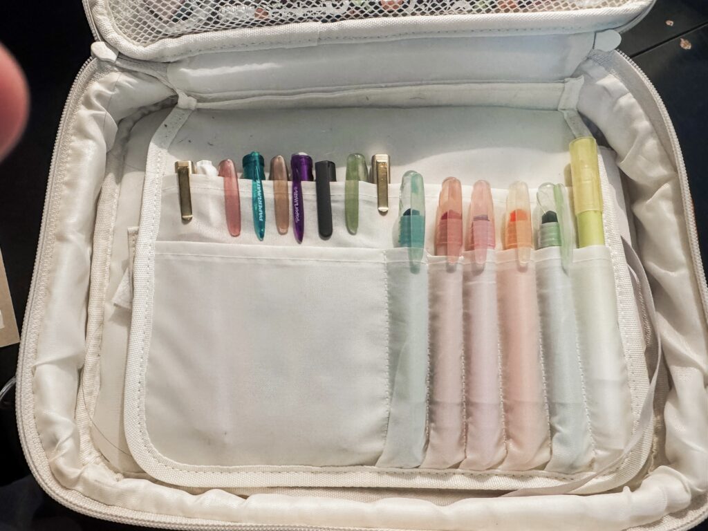 A collection of colorful pens and highlighters organized in a white travel case, ideal for journaling, note-taking, or creative projects.