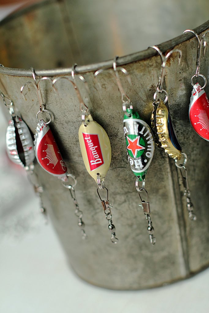 A collection of keychains featuring vintage beer labels from brands like Budweiser, Heineken, and Corona hanging on a metal bucket, showcasing a rustic and nostalgic theme.