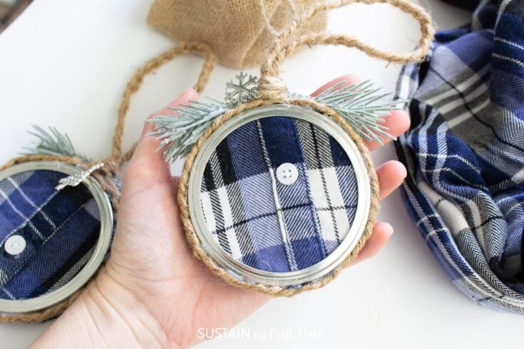 Close-up of a handmade Christmas ornament featuring a plaid fabric background, twine, and decorative pine branches, perfect for holiday decor and festive celebrations.