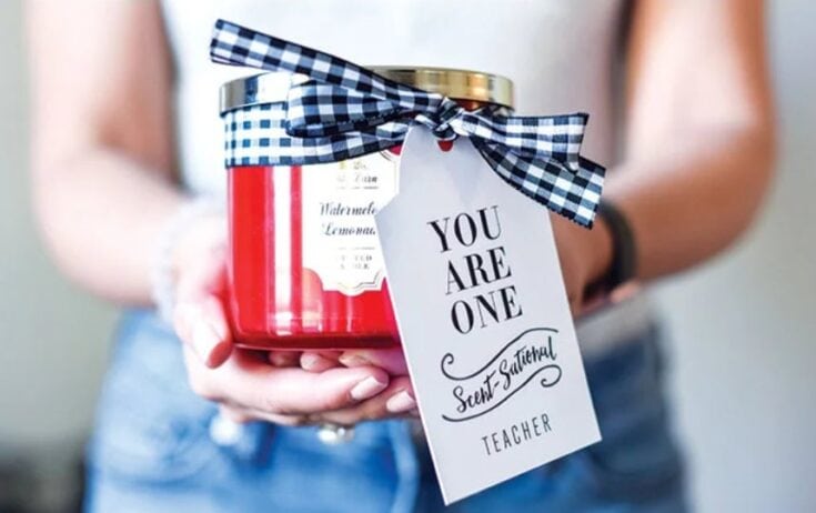 Close-up of a teacher gift featuring a red candle jar with a black and white checkered ribbon and a tag that says 'You Are One' for Teacher Appreciation.