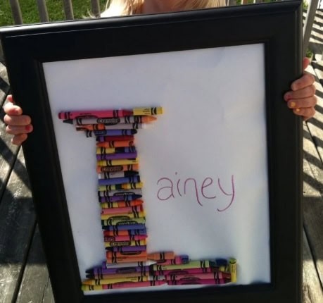 Colorful crayon art in the shape of the letter T with the name Ainey written beside it, perfect for personalized gifts or children's artwork displays.