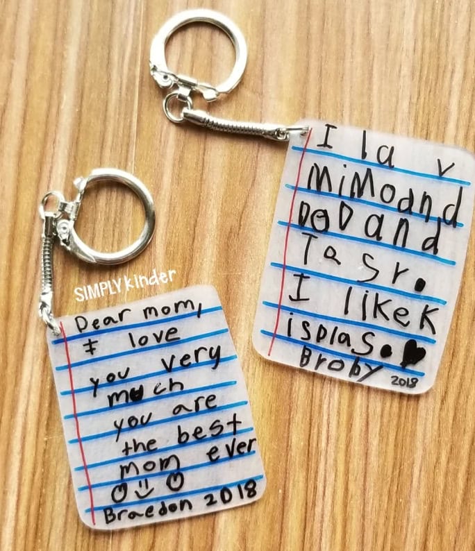Two keychains with handwritten notes from kids to their mom, expressing love and appreciation, on a wooden surface, perfect for heartfelt gift ideas.
