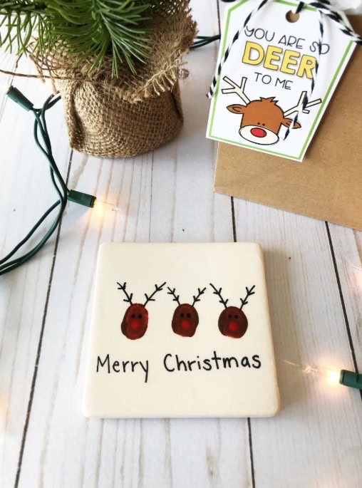 Decorative white chocolate cookie with three reindeer faces and 'Merry Christmas' written below, perfect for holiday gift-giving.