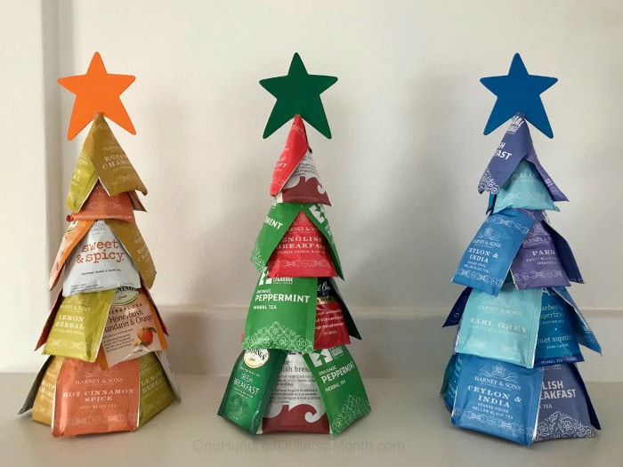 Three decorative Christmas trees made from colorful tea bags, each topped with a star, arranged in a row on a white background for festive holiday decor.
