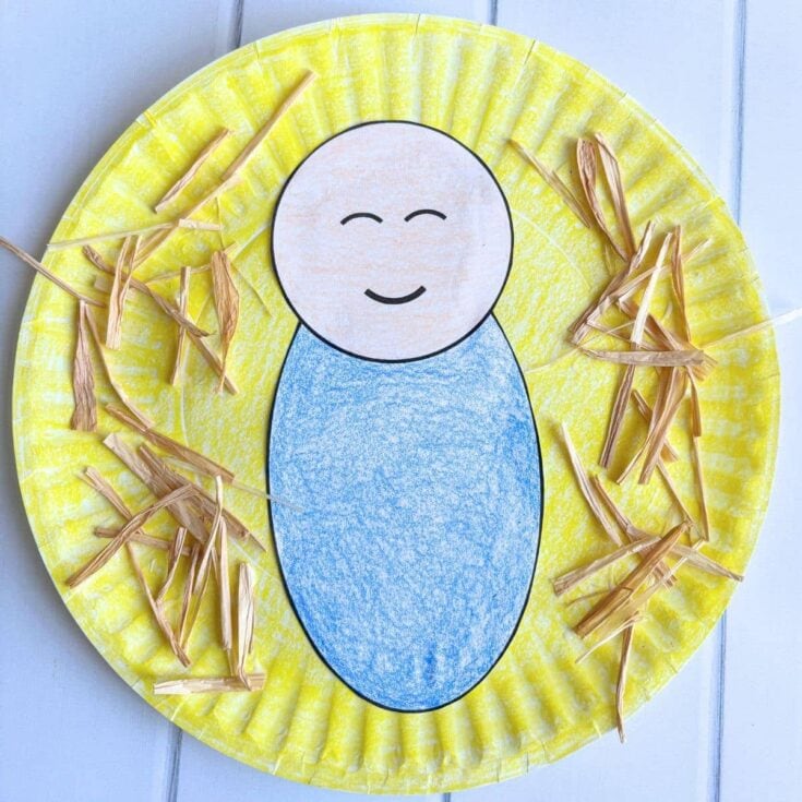 Handmade paper plate craft featuring a smiling baby face with yellow background and decorative straw accents, perfect for children's art projects.