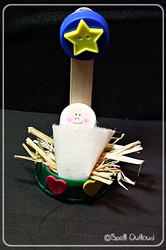 Adorable baby Jesus figurine made of felt and wood, with a star on top, surrounded by straw and colorful hearts, symbolizing the nativity scene for Christmas decor.