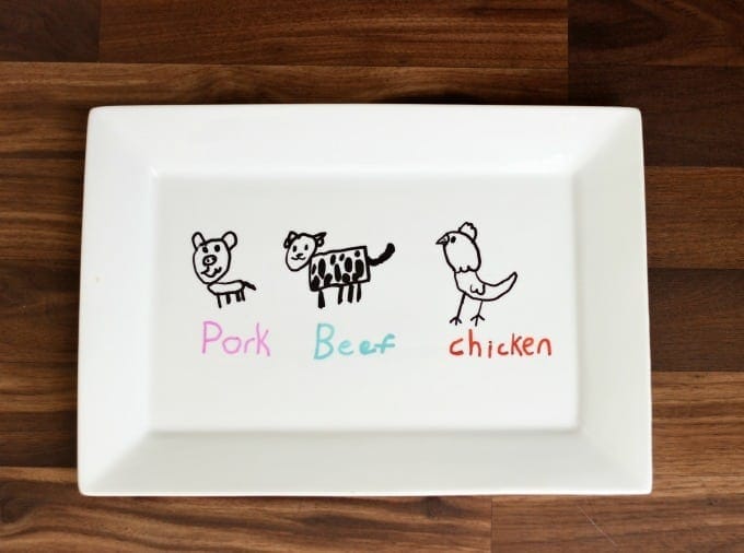 White rectangular plate with hand-drawn pig, cow, and bird labeled Pork, Beef, and Chicken, ideal for children's educational activities or meal labeling.