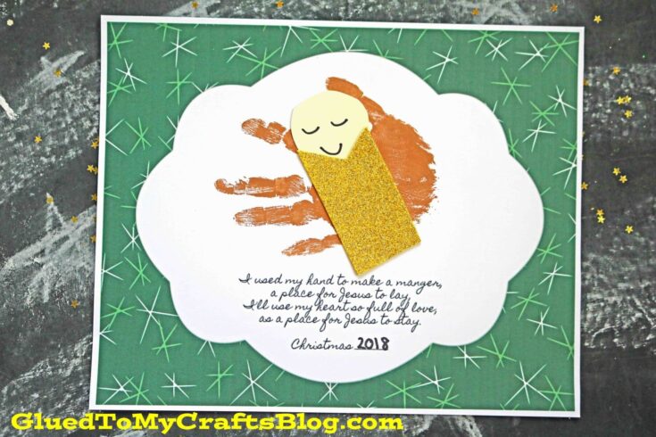 Festive Christmas card featuring a handmade manger scene with a smiling baby Jesus figure made from paper and glitter, on a green background with star patterns.