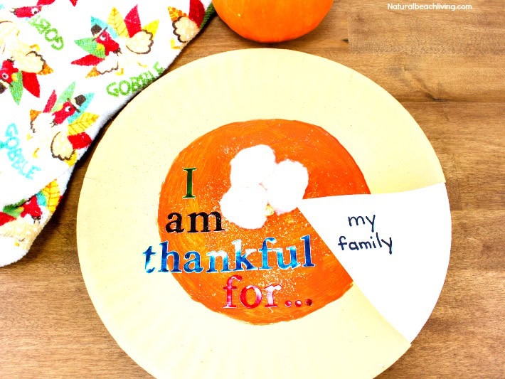 Colorful ceramic plate with the words "I am thankful for... my family" in vibrant colors, placed on a wooden table with a festive cloth nearby, celebrating gratitude and family.