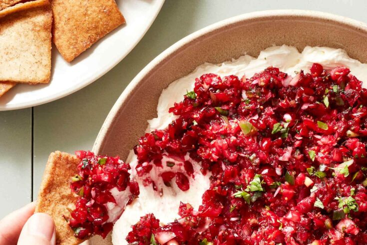 Close-up of a beet and cream cheese dip topped with herbs, served with square crackers on a white plate, perfect for appetizers or snacks.