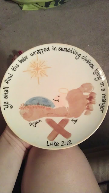Hand-painted decorative plate featuring a nativity scene with a star, a manger, and the words from Luke 2:12, 'He shall find the babe wrapped in swaddling clothes, lying in a manger'.