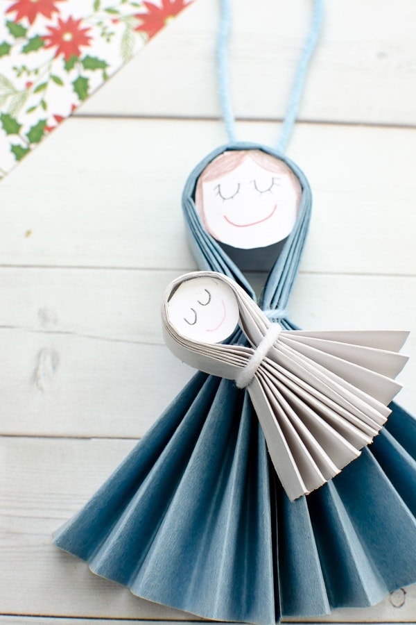 Colorful paper angel craft made from folded paper and paper plate, featuring smiling faces, perfect for children's arts and crafts activities.