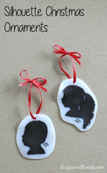 Two DIY silhouette Christmas ornaments with red ribbons, featuring black paper cutouts of children's profiles on white background, perfect for holiday decor.