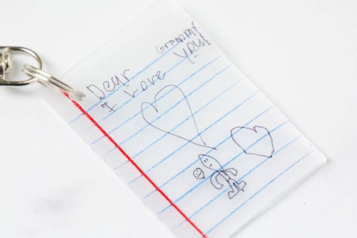 A child's handwritten note on lined paper with a red margin, expressing love to grandma with a heart drawing and a small stick figure, symbolizing affection and innocence.