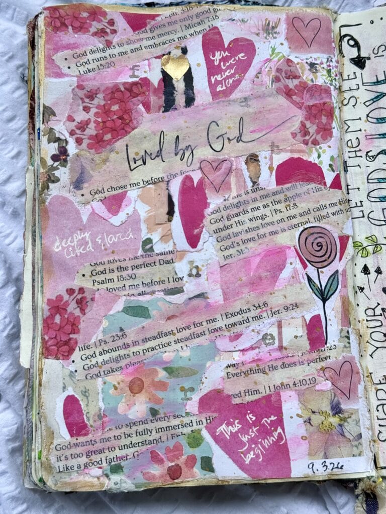Mixed media collage in a journal with pink hearts, flowers, and handwritten notes expressing love and faith, inspired by biblical verses and spiritual themes.