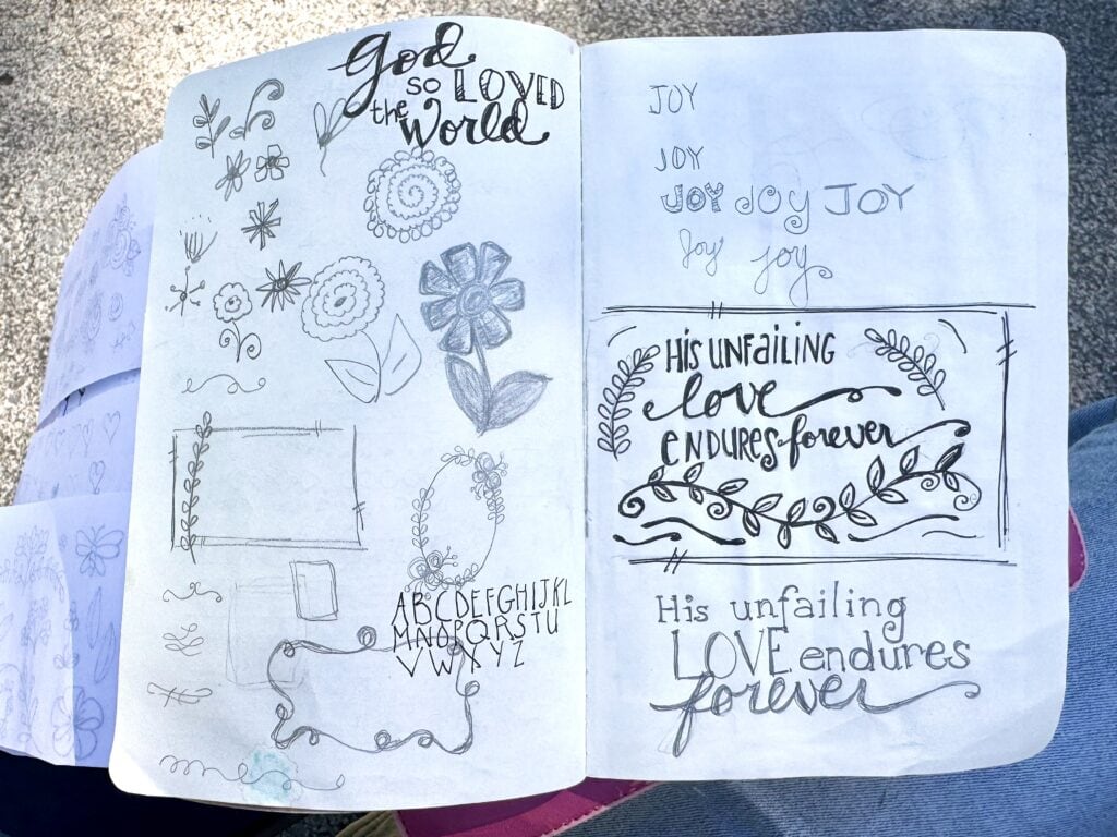 Handwritten inspirational quotes and floral doodles in a journal, emphasizing love, joy, and enduring faith with artistic sketches and calligraphy.