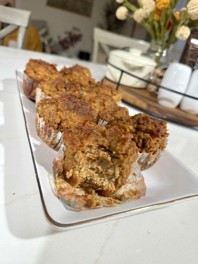 Close-up of freshly baked banana pumpkin muffins on a glass tray, showcasing their golden-brown crust and moist interior, perfect for breakfast or snack.