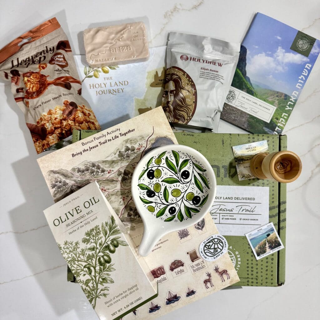 Assorted Holy Land tea and olive oil gift set featuring green olive branch motif on a decorative plate, with travel brochures, sachets, and a cup of coffee, showcasing a curated collection 